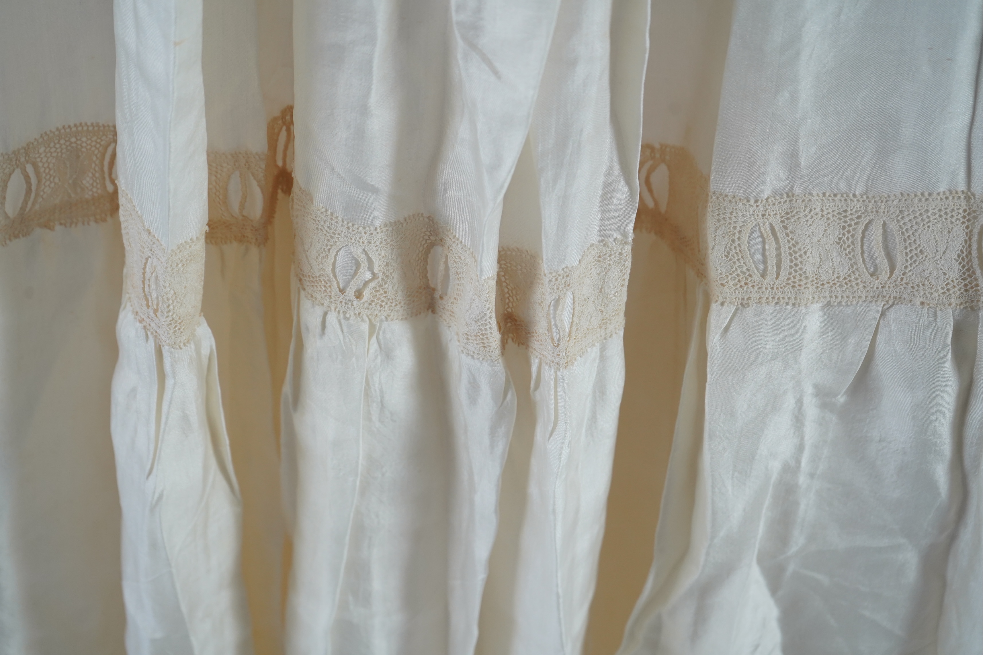 A suitcase containing a cream silk lace skirt to a dress, an Edwardian silk petticoat and various collars, possibly for theatrical use, silk petticoat 96 cm long. Condition - fair